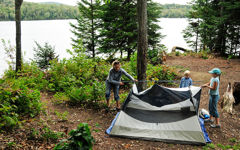 A family pitches a tent at a paddle-in campsite—a great option for those looking for tent-only campgrounds.
